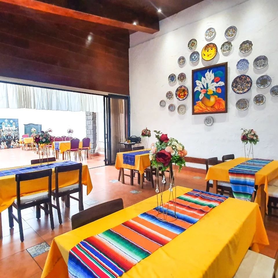 Salón con mantelería colorida y arte salvadoreño en las paredes