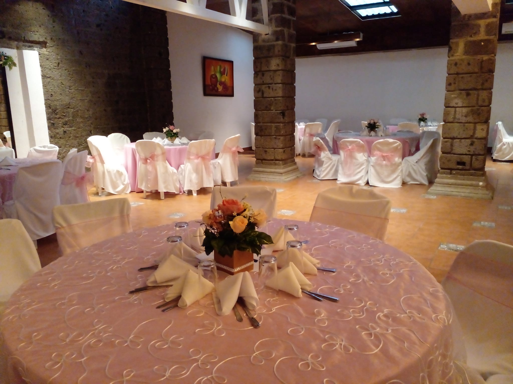 Salón de El Patio montado en tonos rosados con columnas de piedra