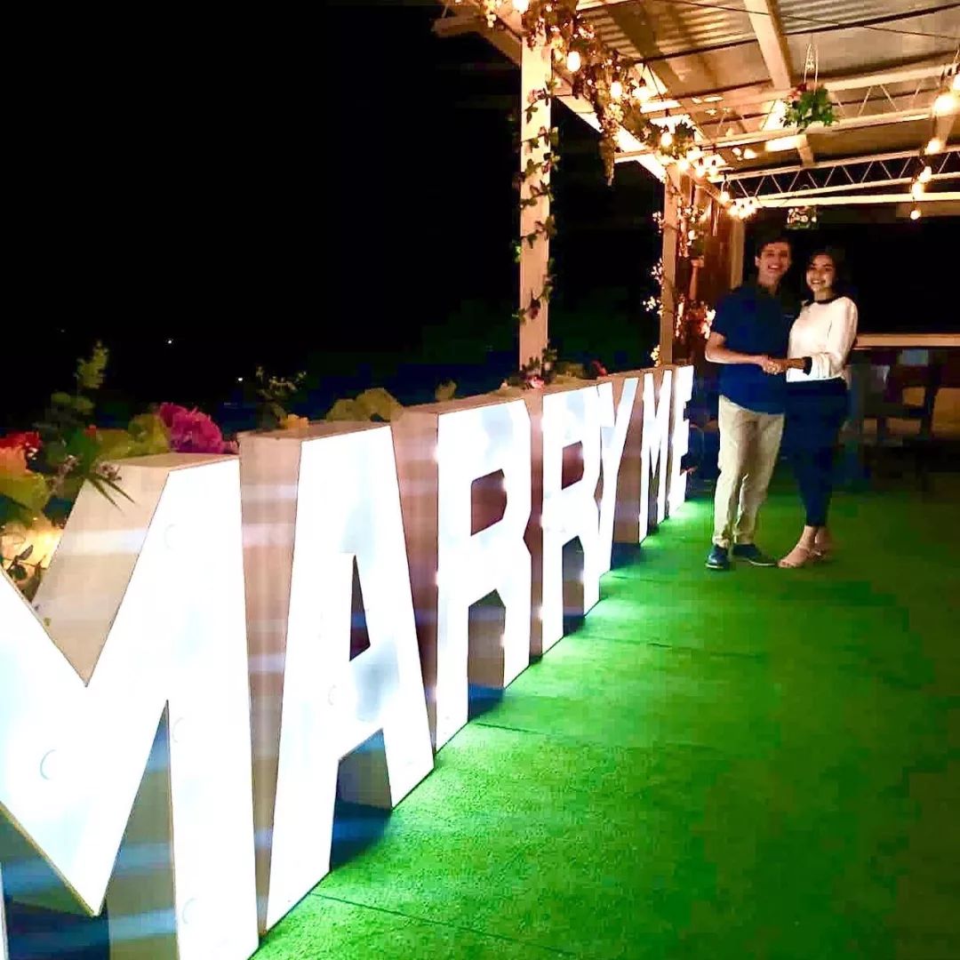 Propuesta de matrimonio en el Skygarden de El Patio, con letrero "Marry Me" iluminado